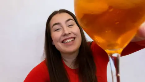 Young Female Student Talking and Raising Glass Directly to Camera