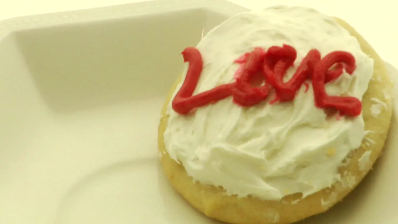 A woman's hand picks up a cookie with the word Love on it spelled out in icing