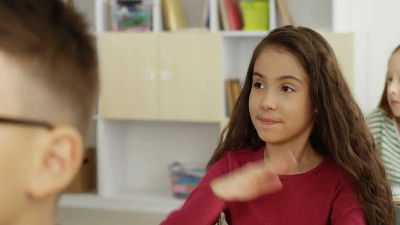 Close Up Of The Nice Teen Small Schoolgirl Answering The Teacher Question With Rised Hand In The School At The Lesson