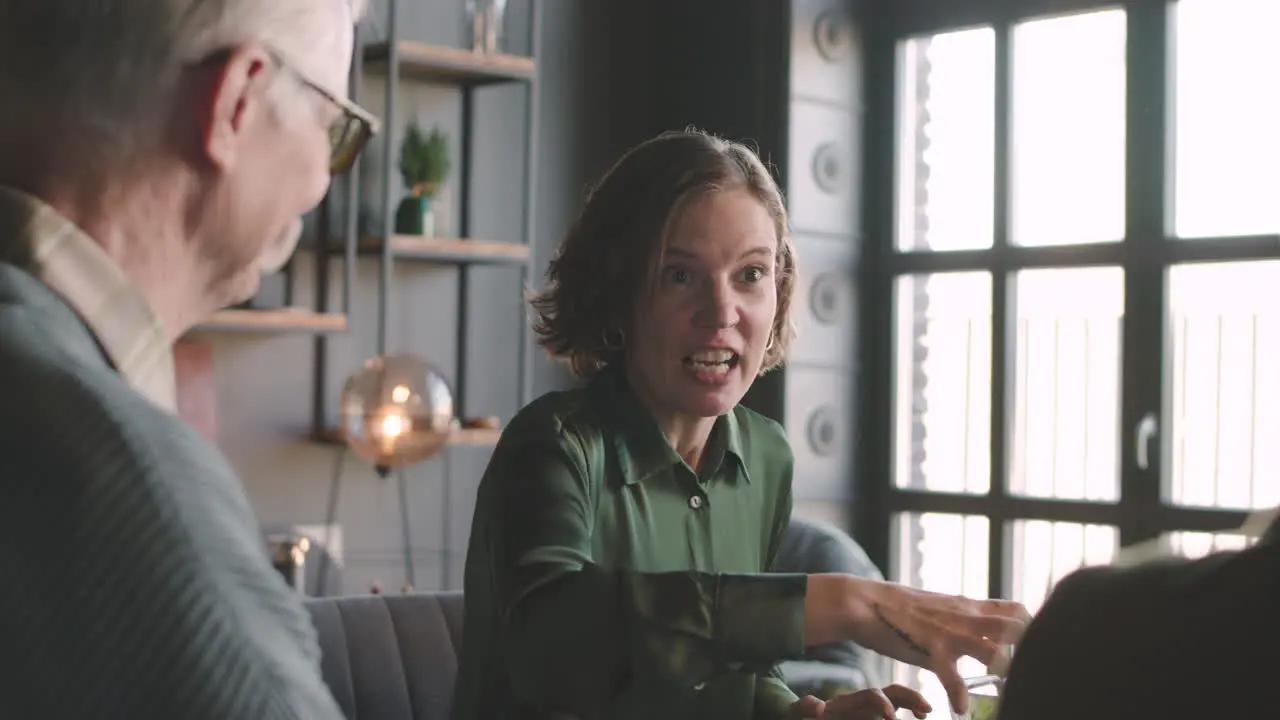 Happy Woman Talking To Her Family While Sitting At Table And Having A Meal Together At Home