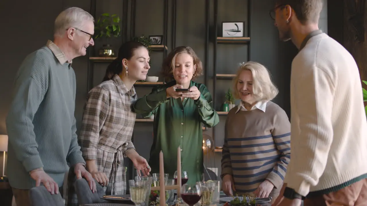 Woman Taking Photo Of Food On Table During A Family Reunion At Home