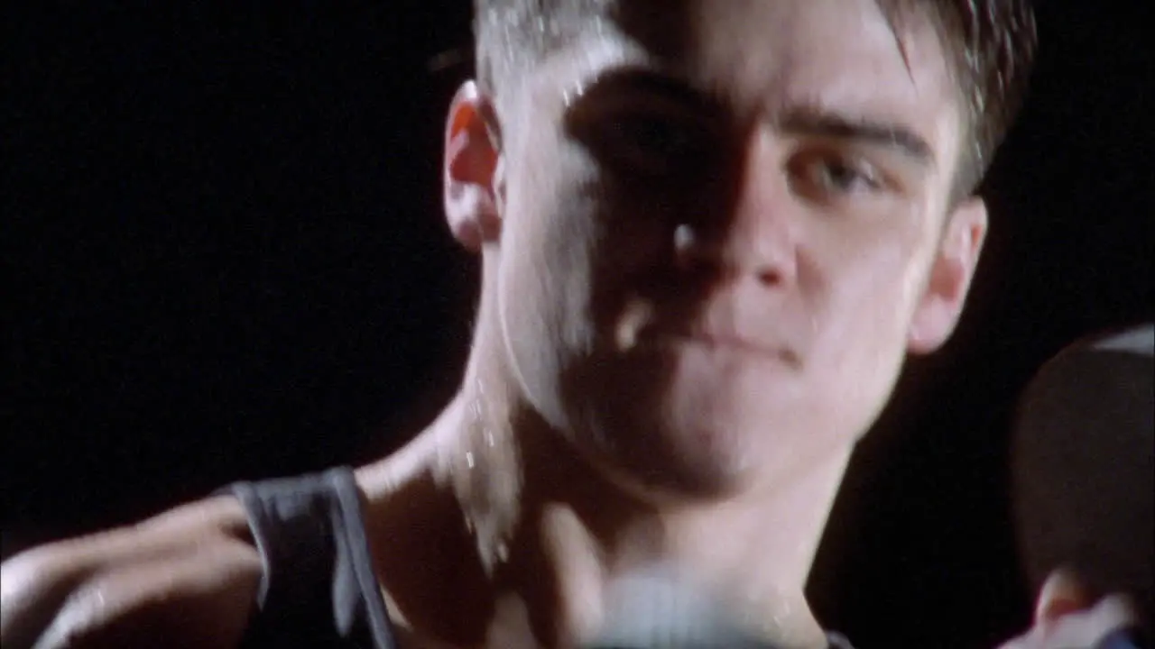 A young man exercises with a dumbbell in each hand