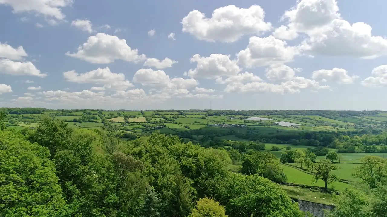 Aerial tracking sideways in amongst trees looking out across gorgeous spring Devon landscape