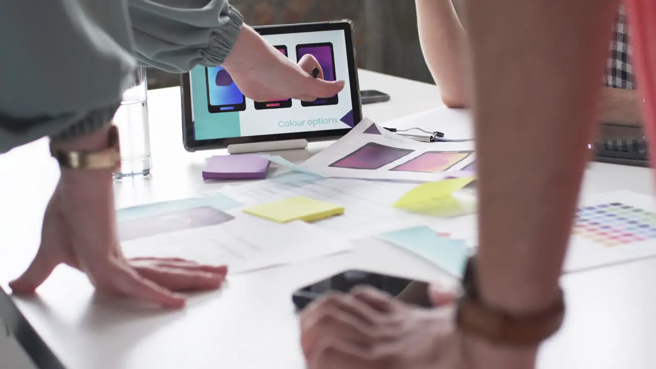 Creative professionals in the business are examining color options on a computer screen surrounded 