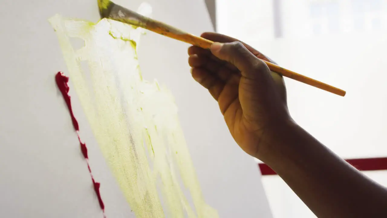 Close up of hand of male artist painting on canvas at art studio