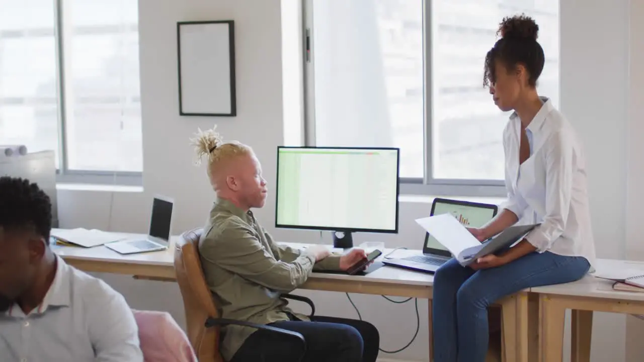 Diverse business people discussing with computer in creative office