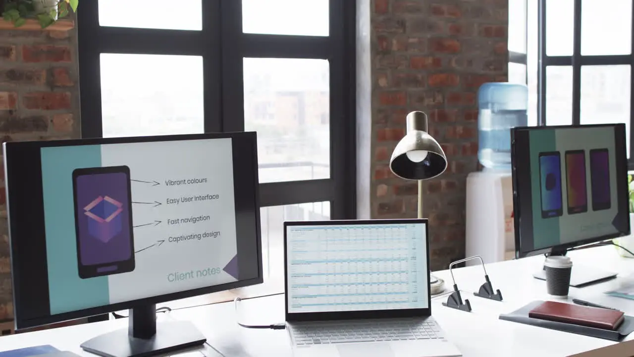 Modern office desk in a business setting is equipped with a laptop monitor and presentation screen