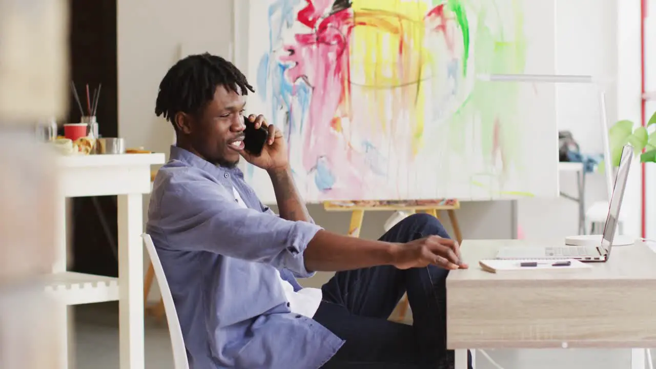 African american male artist talking on smartphone at art studio