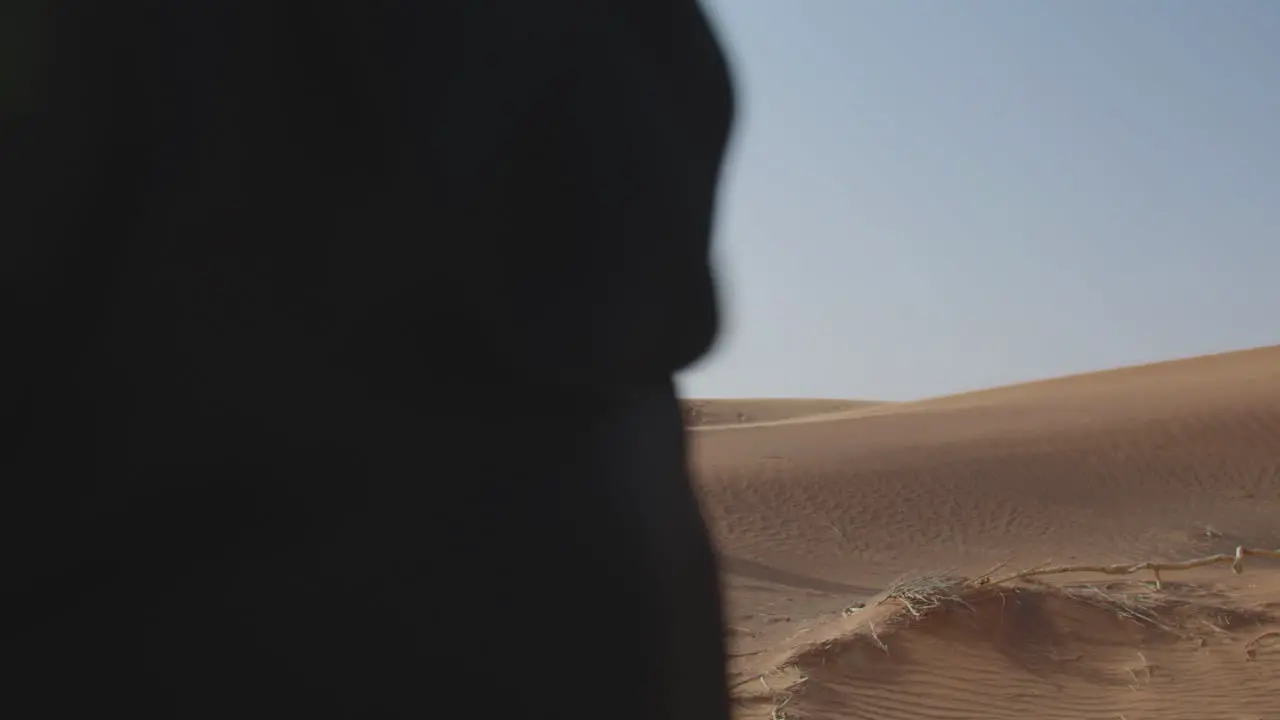 Two Muslim Women Wearing Traditional Dress And Hijab Walking In A Windy Desert