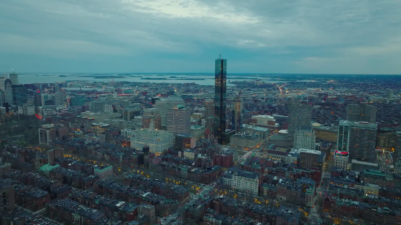 Aerial panoramic footage of modern tall skyscraper and surrounding downtown buildings Evening shot of large city Boston USA