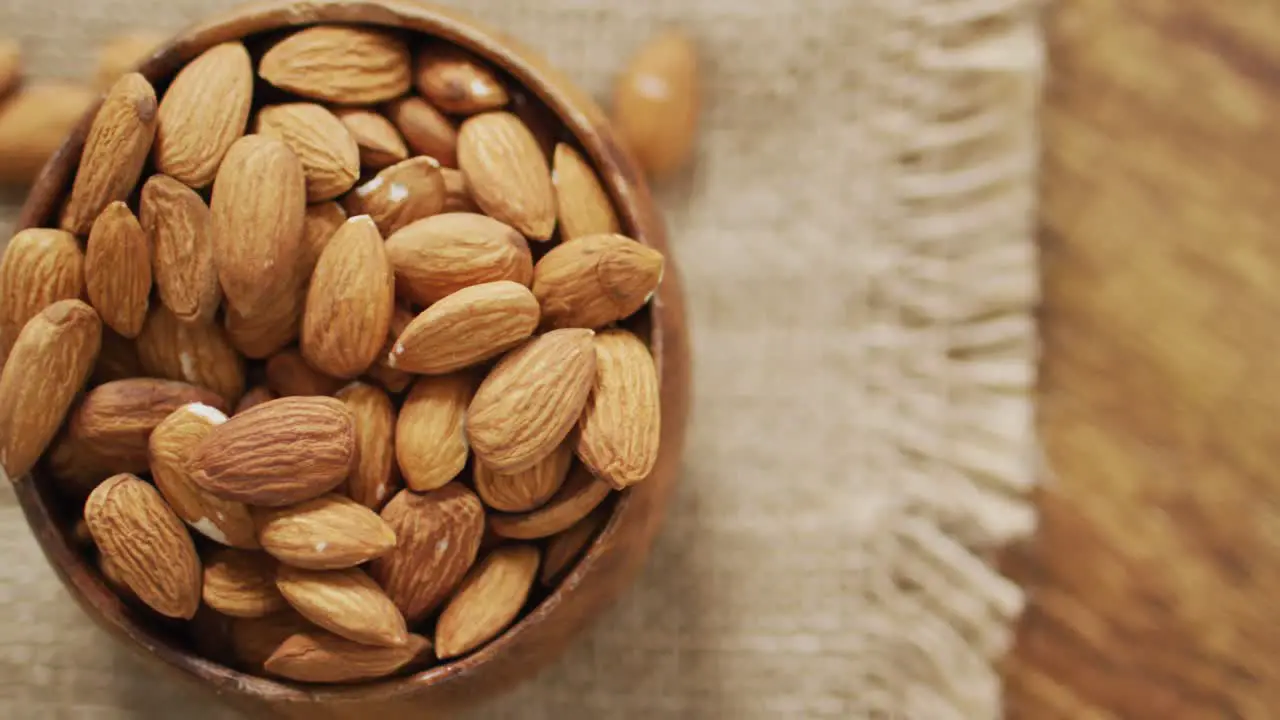 Video of almonds in a bowl on wooden background