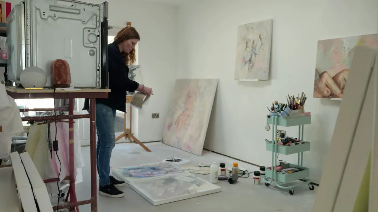 Female artist prepping paper asset on canvas in a home studio