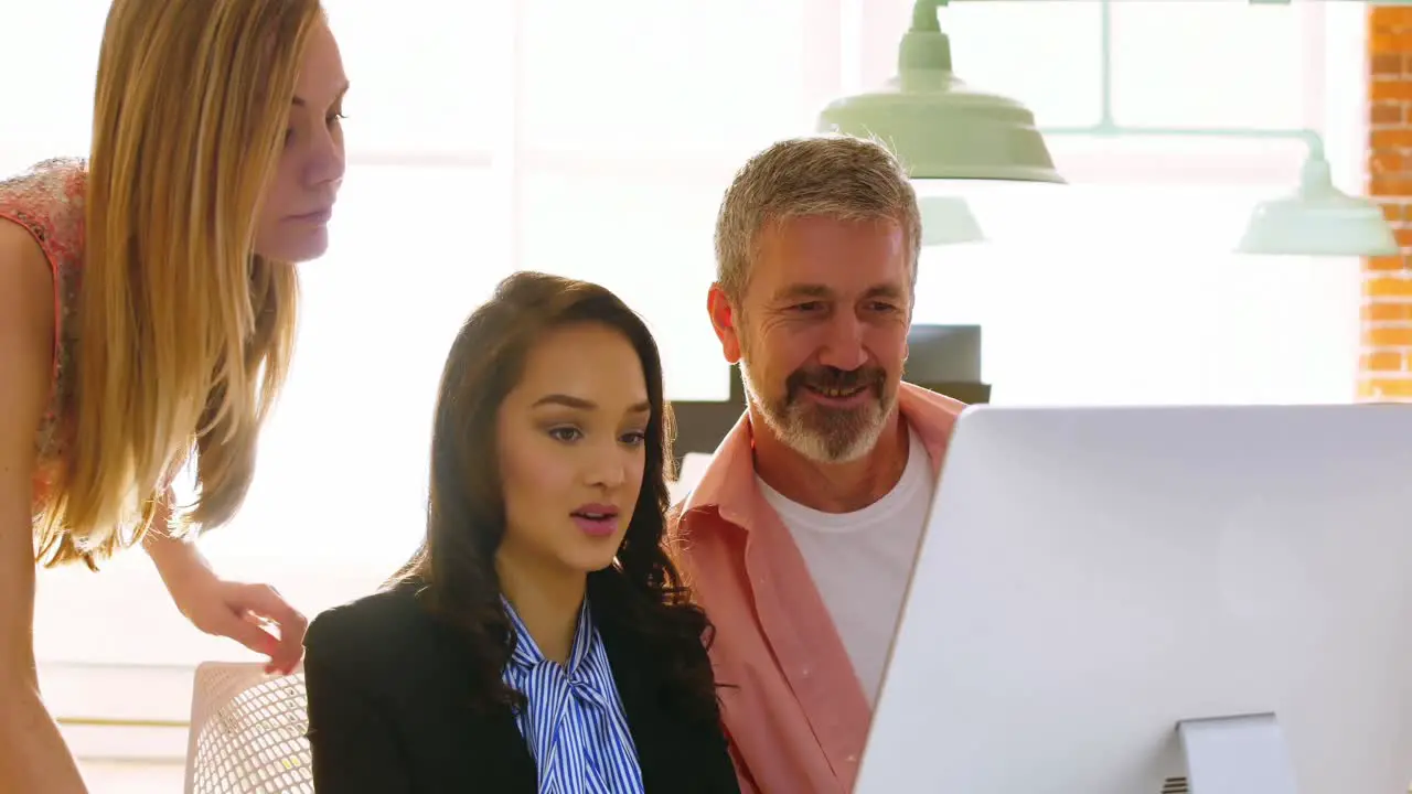 Male and female executives discussing over computer