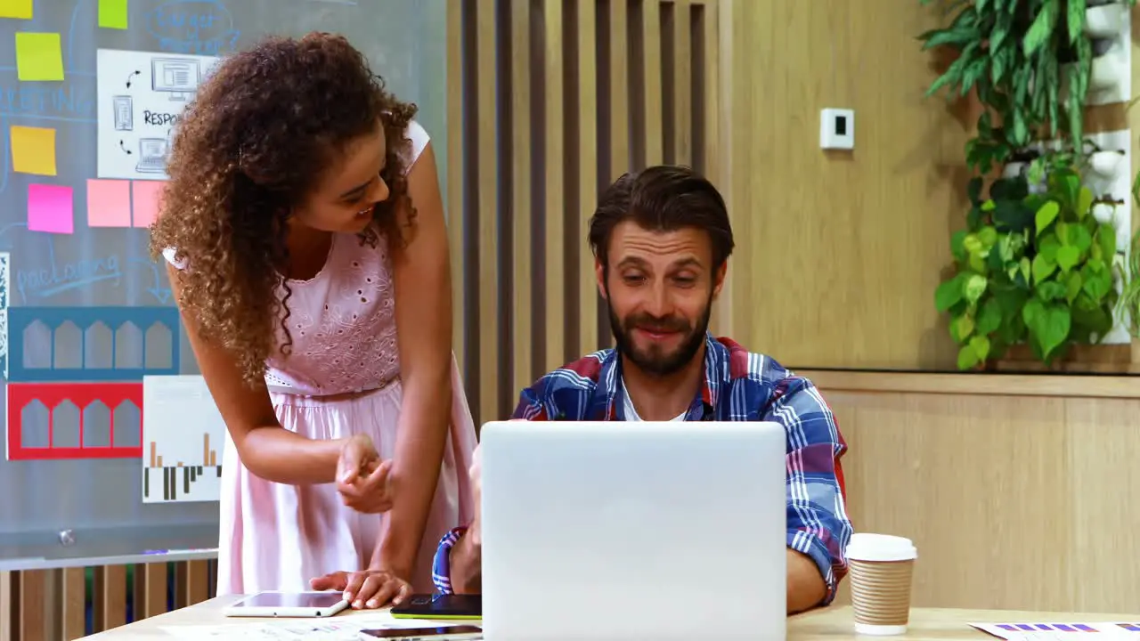 Two executives discussing over laptop at desk