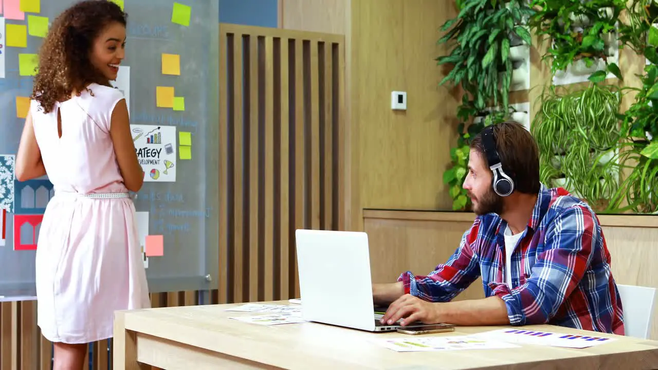 Executives discussing with each other while using laptop