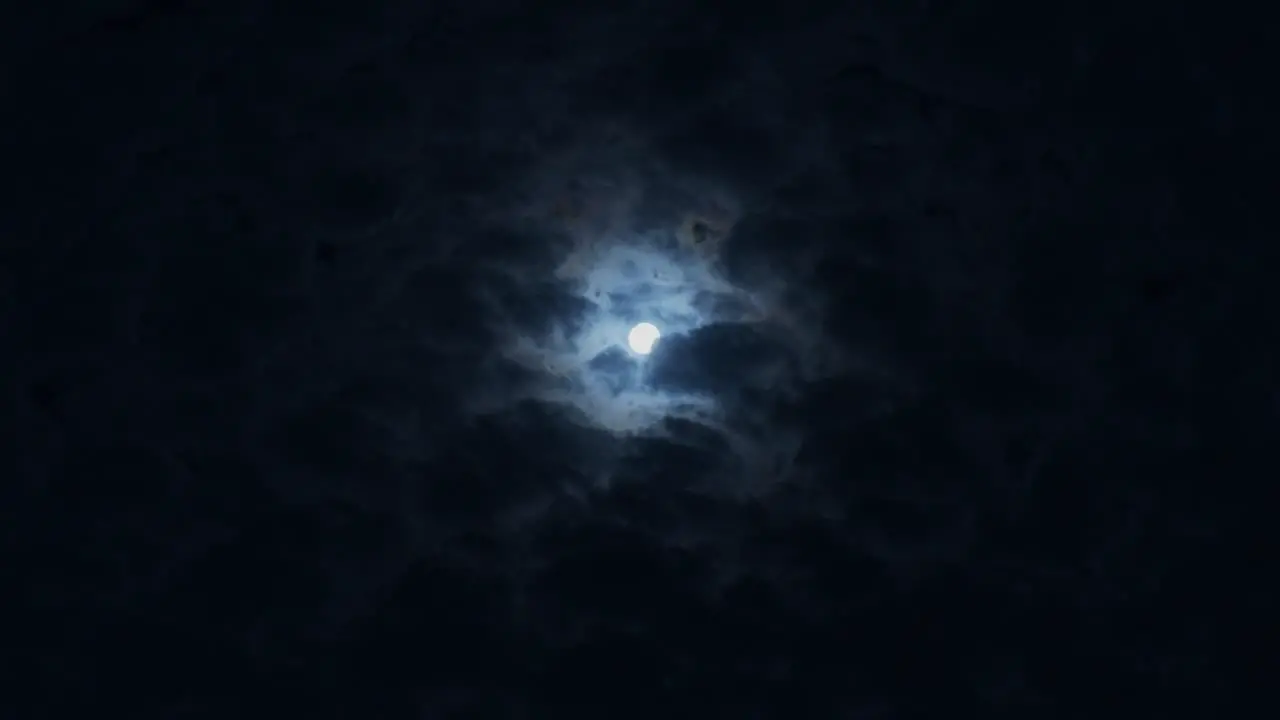 moon in the night sky with fast running clouds