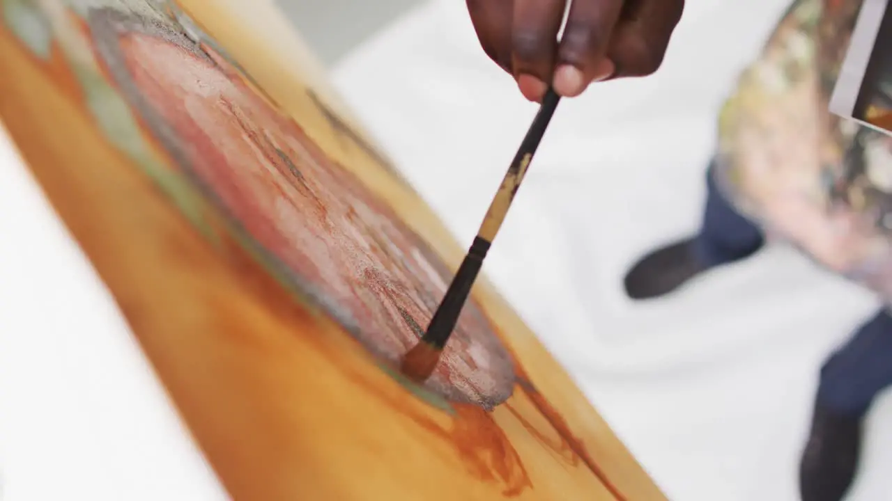 Overhead view of male artist painting on canvas looking at photo at art studio