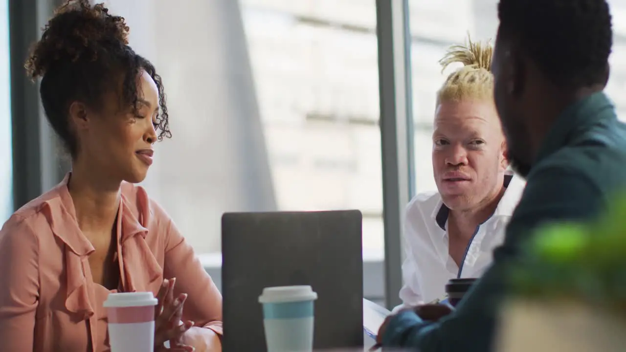 Diverse business people discussing with takeaway coffee and documents in creative office