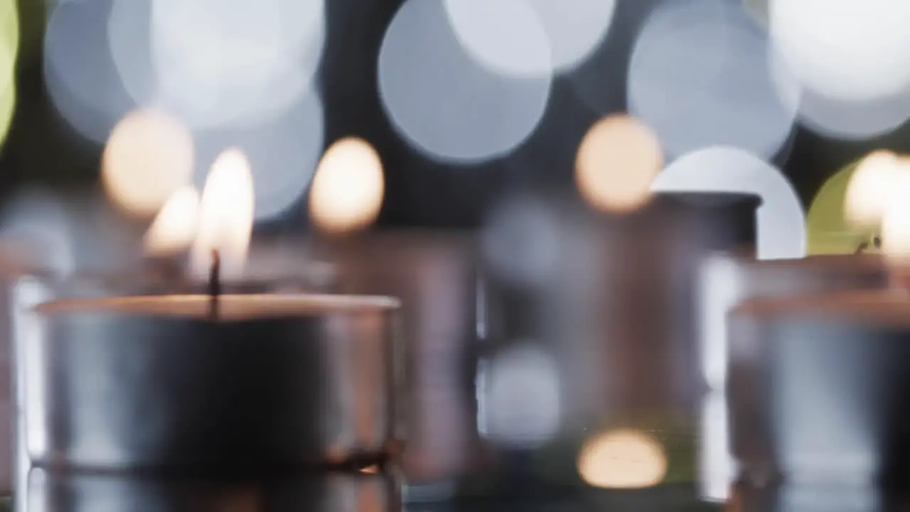 Video of tea candles with white flames and copy space with bokeh on black background