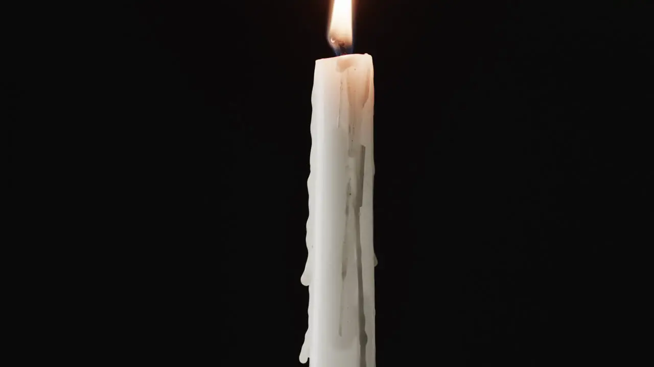 Video of white candle with white flame and copy space on black background