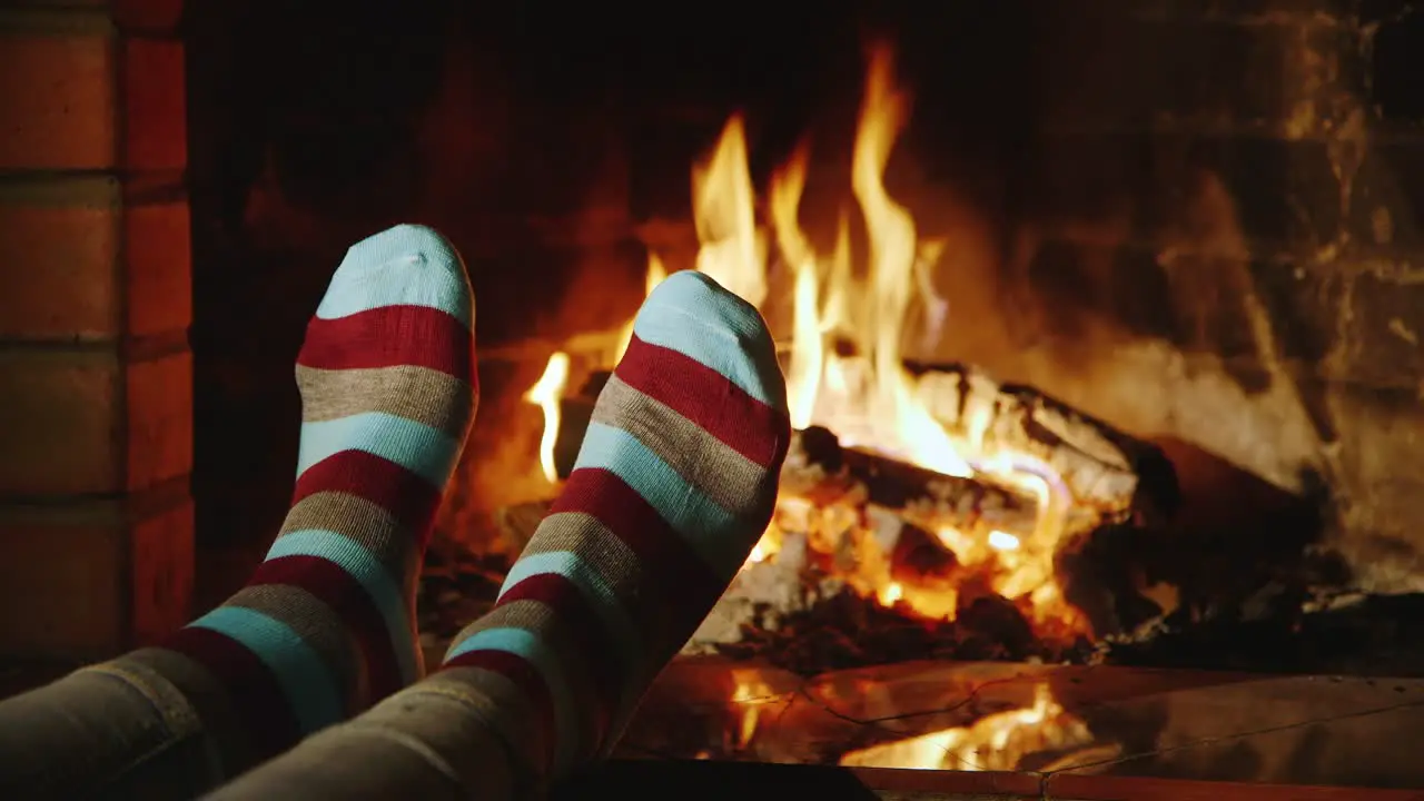 A woman warms her feet by the fireplace