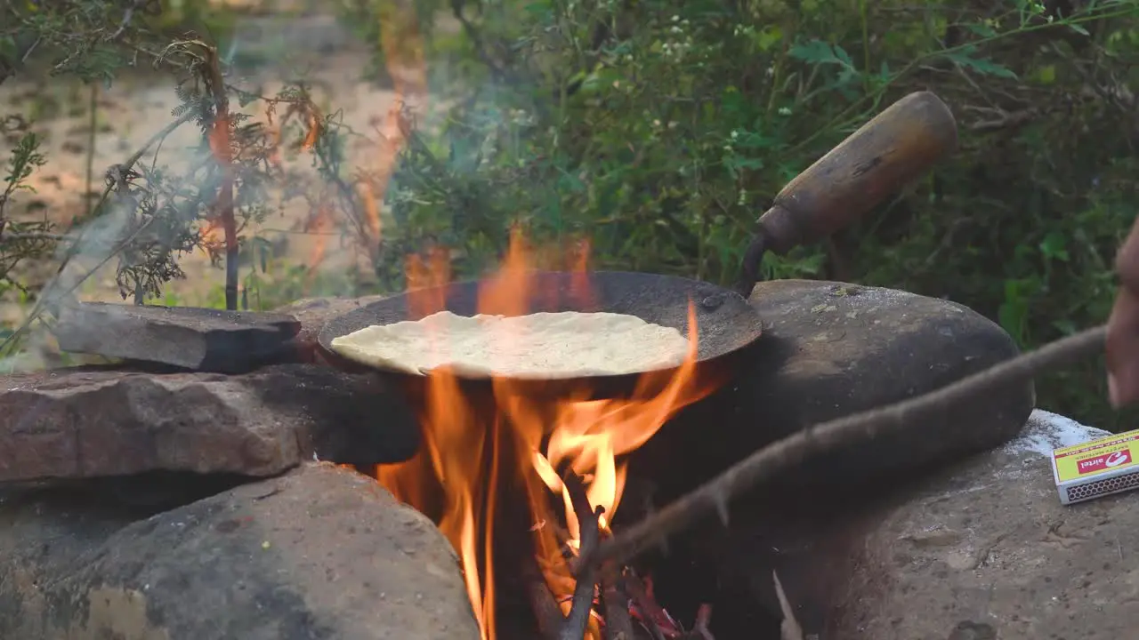 Side shot of Outdoor cooking of Indian food on campfire flames in nature  India