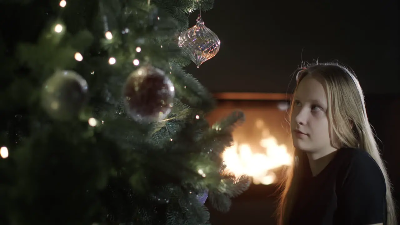 The girl is looking at a beautiful Christmas tree in the background a fire is burning in the fireplace Christmas Eve