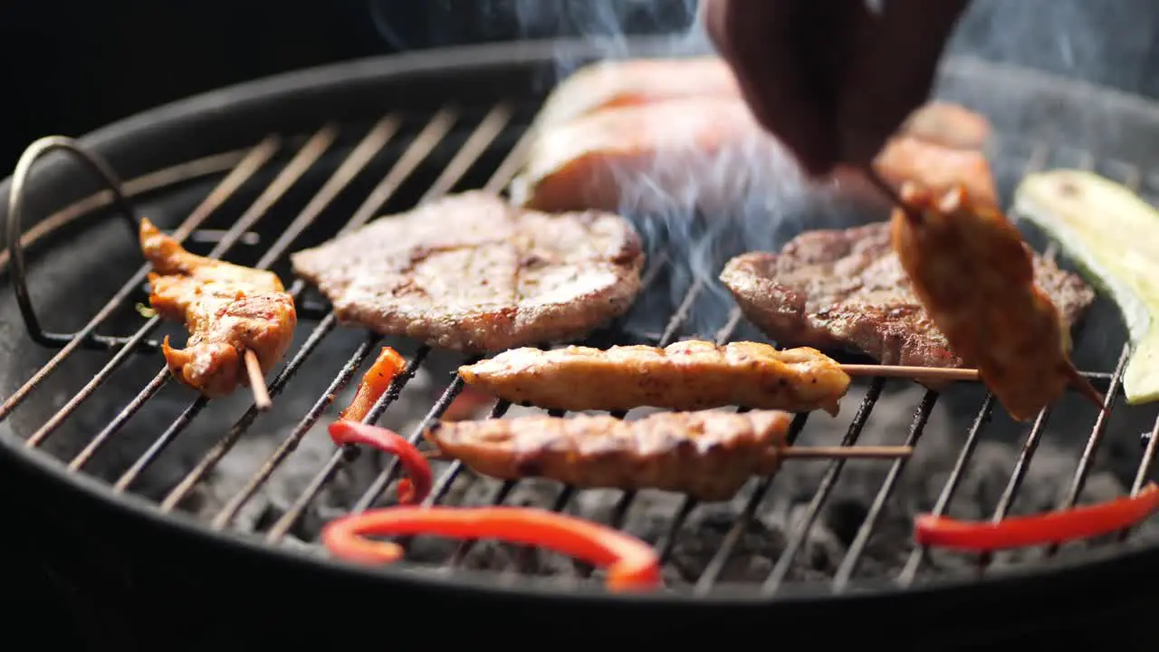 A delicious chicken skewer is turned over by hand on the grill