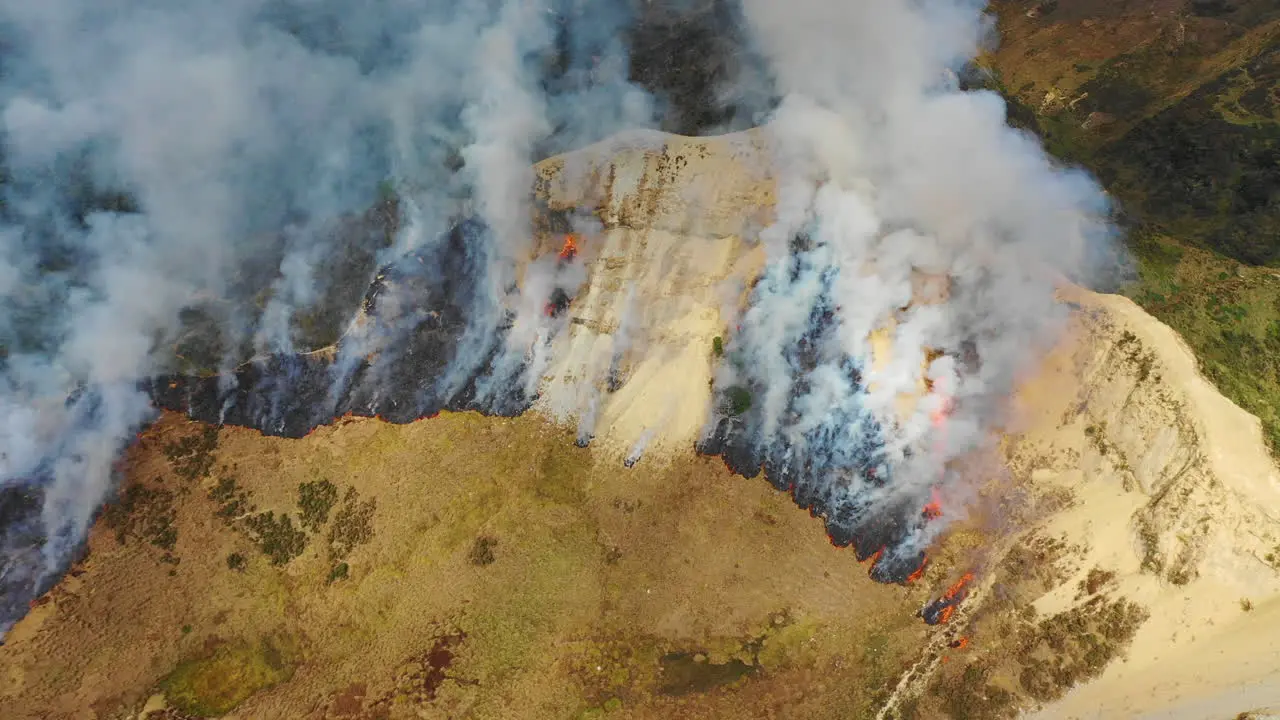 Aerial drone view of smoke rising from a wildfire on a hillside