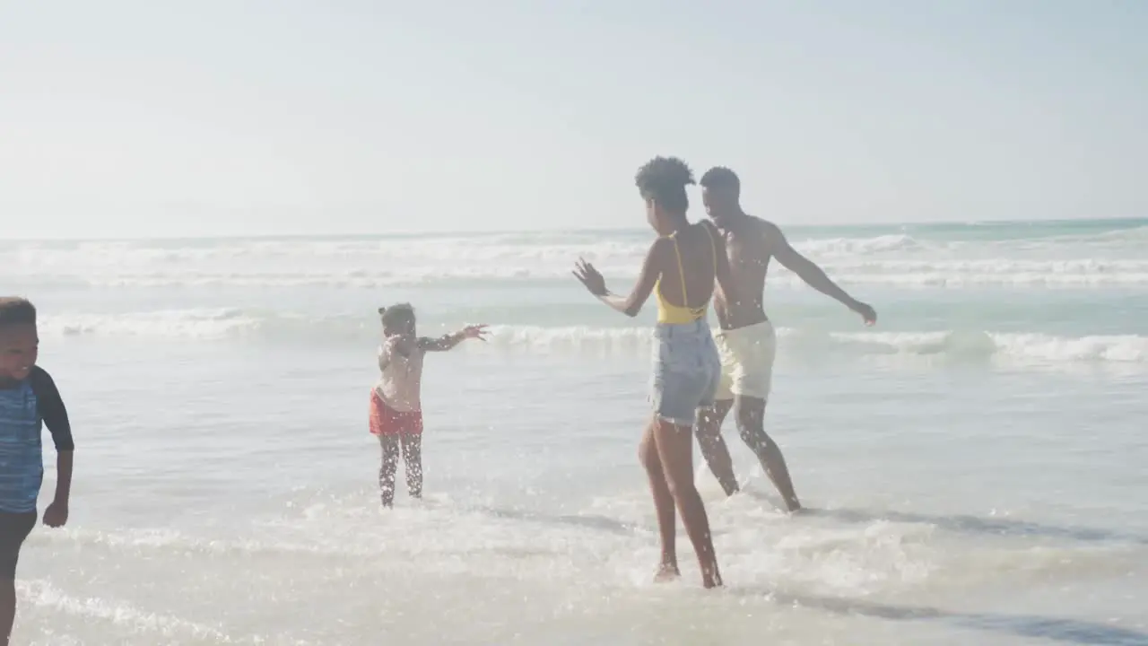 African american family enjoying together near the waves at the beach