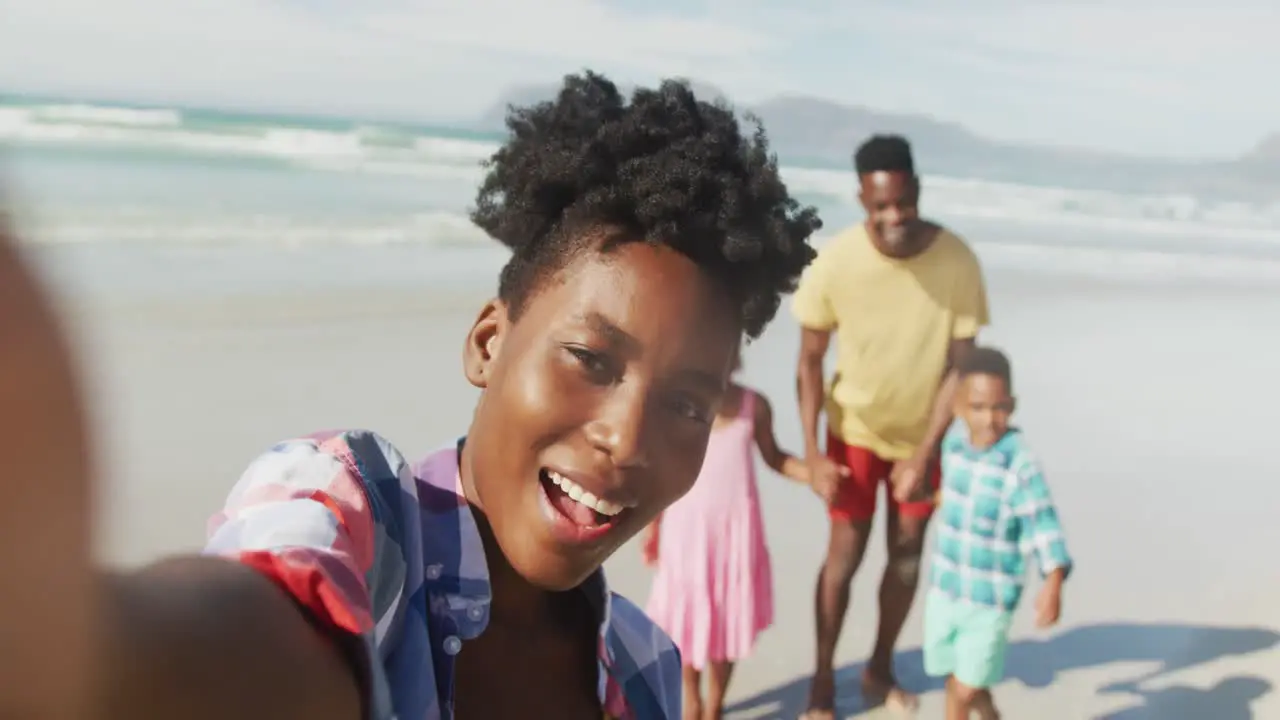 Portrait of african american family smiling while taking a selfie at the beach