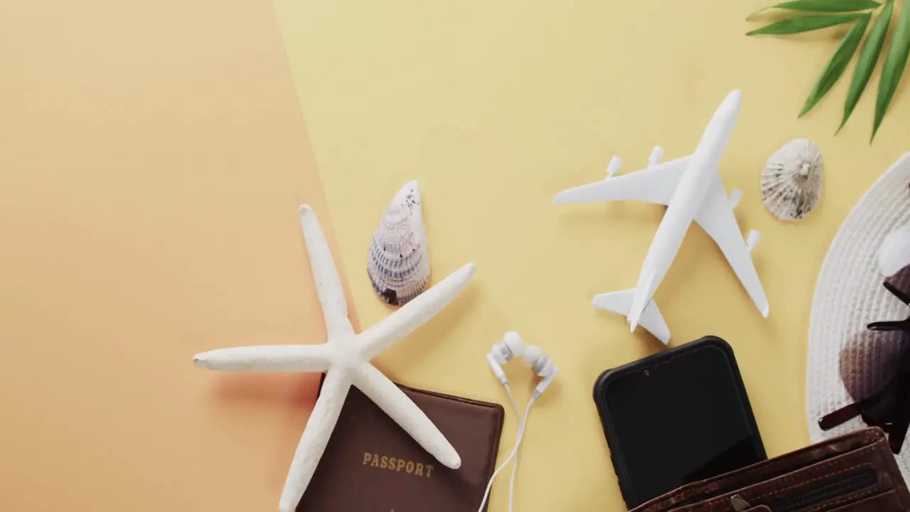 Close up of shells passport plane model smartphone with copy space on yellow background