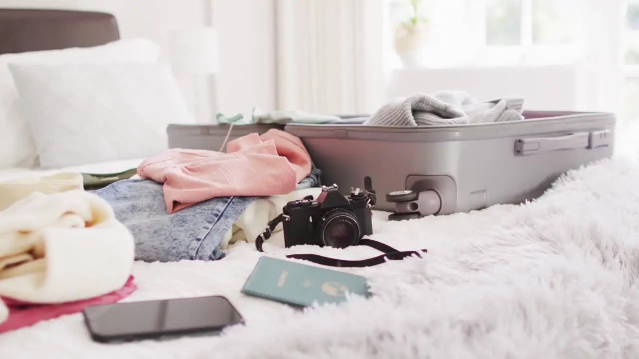 Video of passport smartphone camera clothes and suitcase on bed