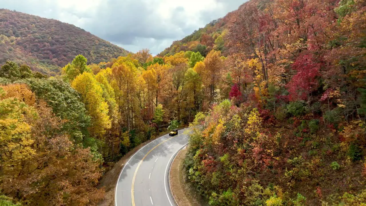 aerial pullout fall foliage with car and motorcycle along roadway in the mountains of northern georgia