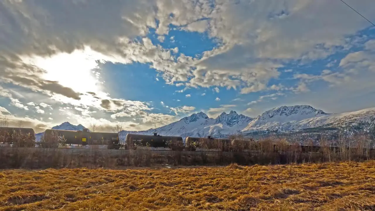 Railroad cargo train passing by snow covered mountains