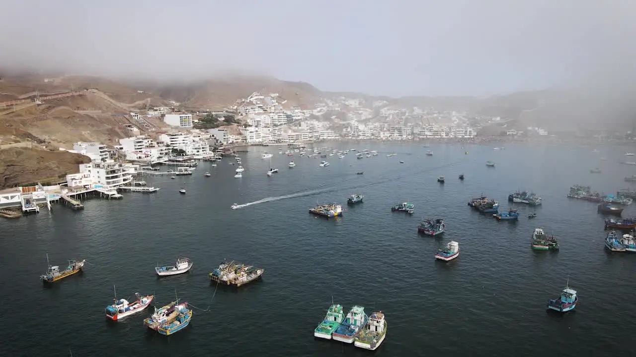 Drone shot of beach houses next to fishing boats and yachst in the coast of Peru in the summer