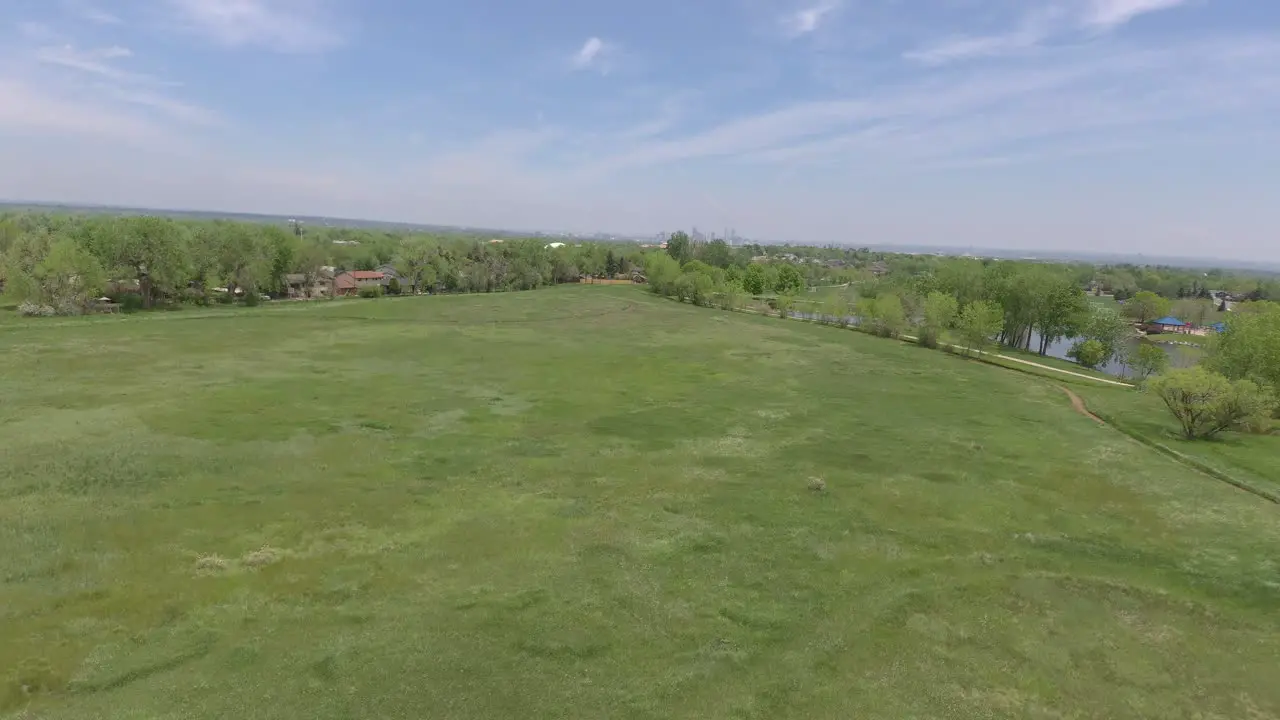 Flight over green grass Denver in the distance