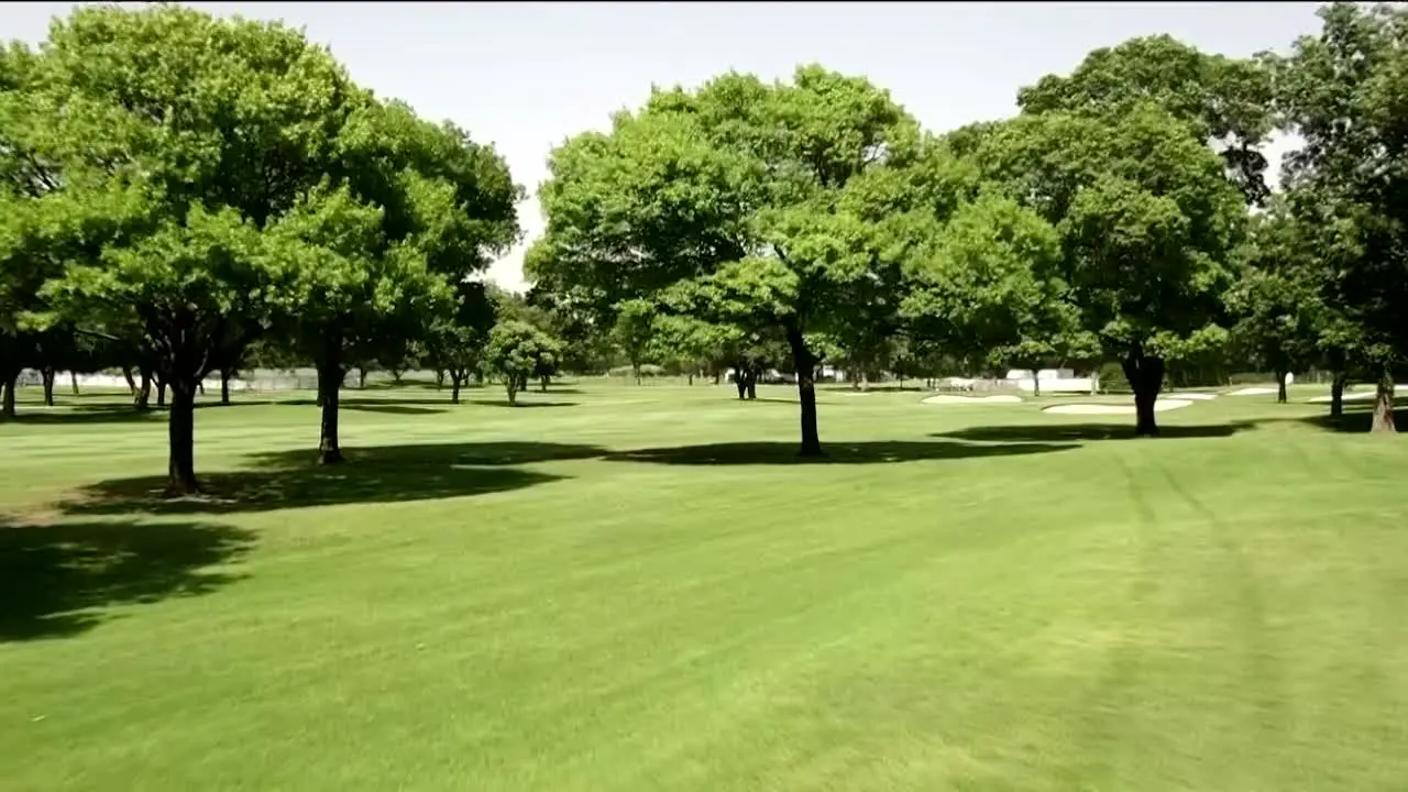 Drone footage of golf course fairway through trees