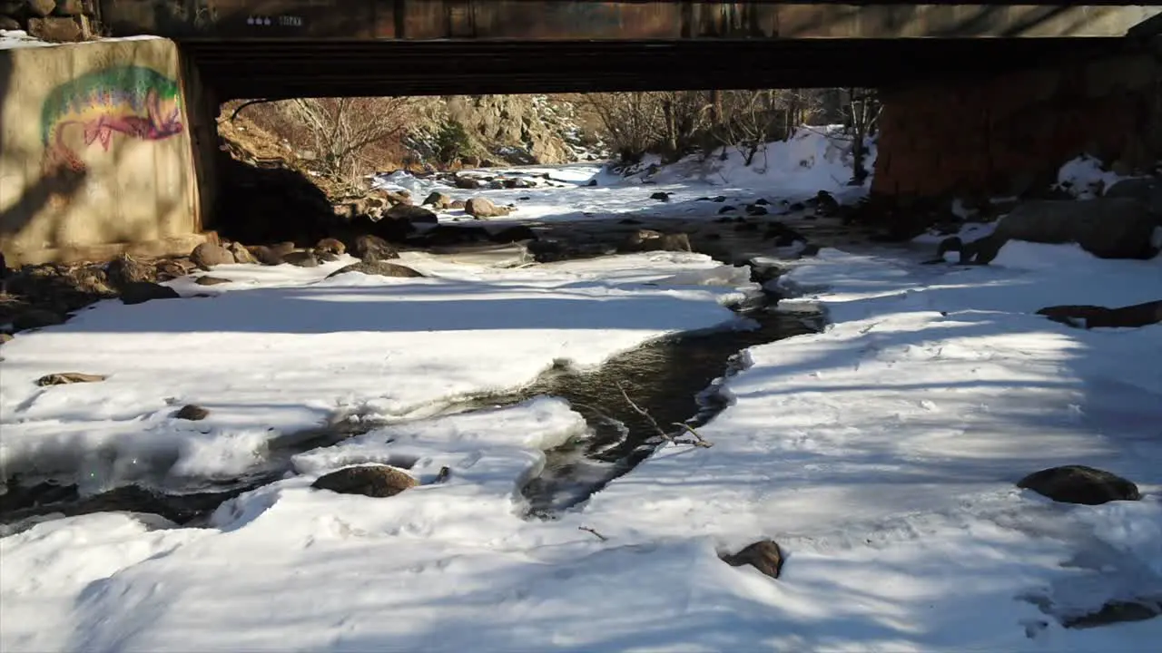 Babbling creek in snowpack under bridge