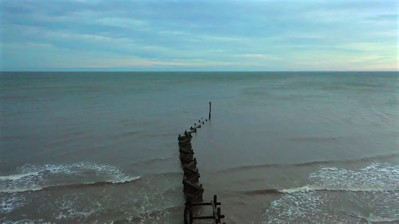 Aerial flight out over crooked sea defences and out to sea