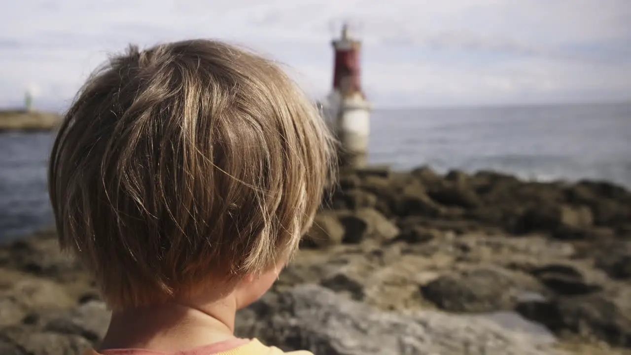 Young boy looking at a lighthouse at the beach