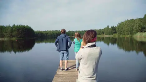 Tourists enjoy view of forest lake standing on wooden bridge Relaxing near river