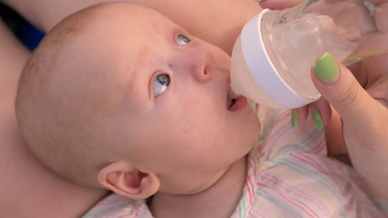 Mom giving baby to drink water from the bottle