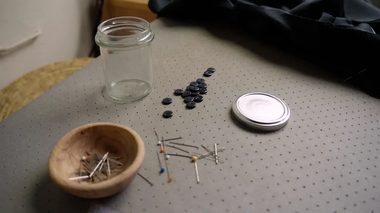 Pot of pins with needle and buttons in seamstress's fashion studio