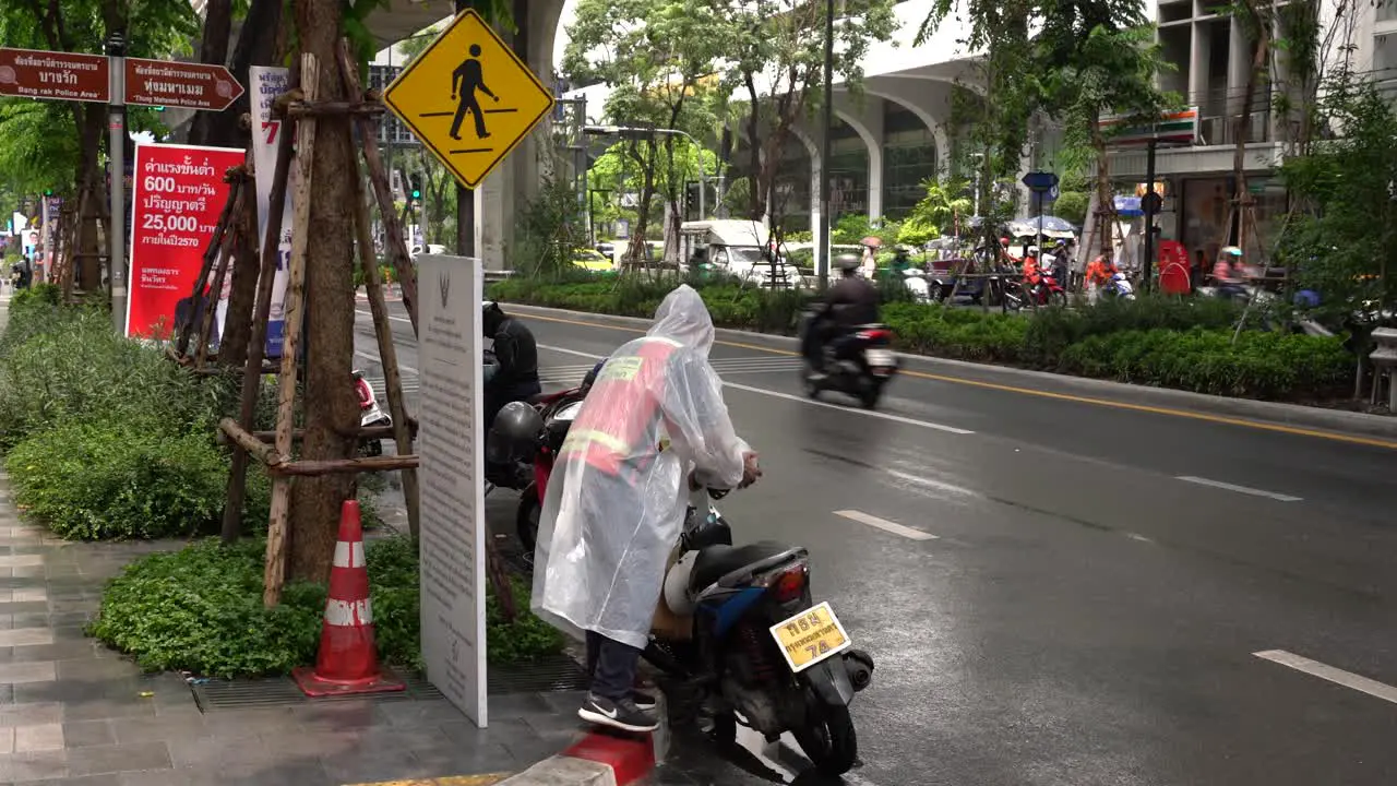 Motorcycle taxi driver wearing raincoats on rainy days parked his bike in Silom Bangkok Thailand