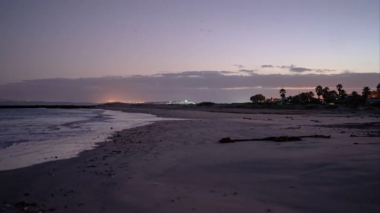 Sunrise Timelapse on the beach with coastal town in the background