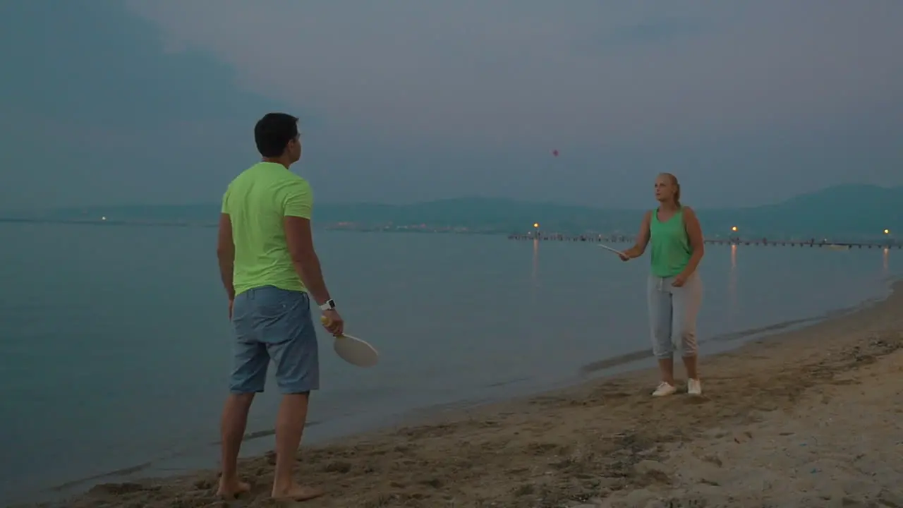 Man and woman playing badminton on seacoast