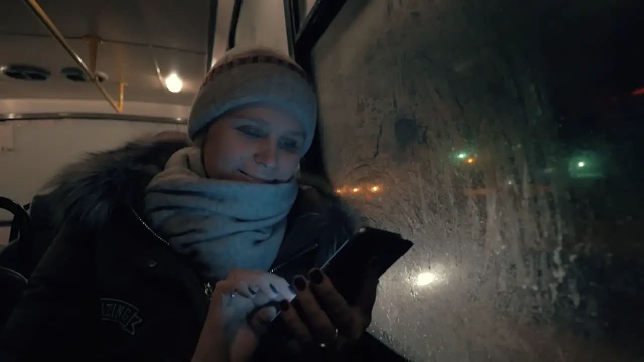 Woman with mobile traveling by bus in winter evening