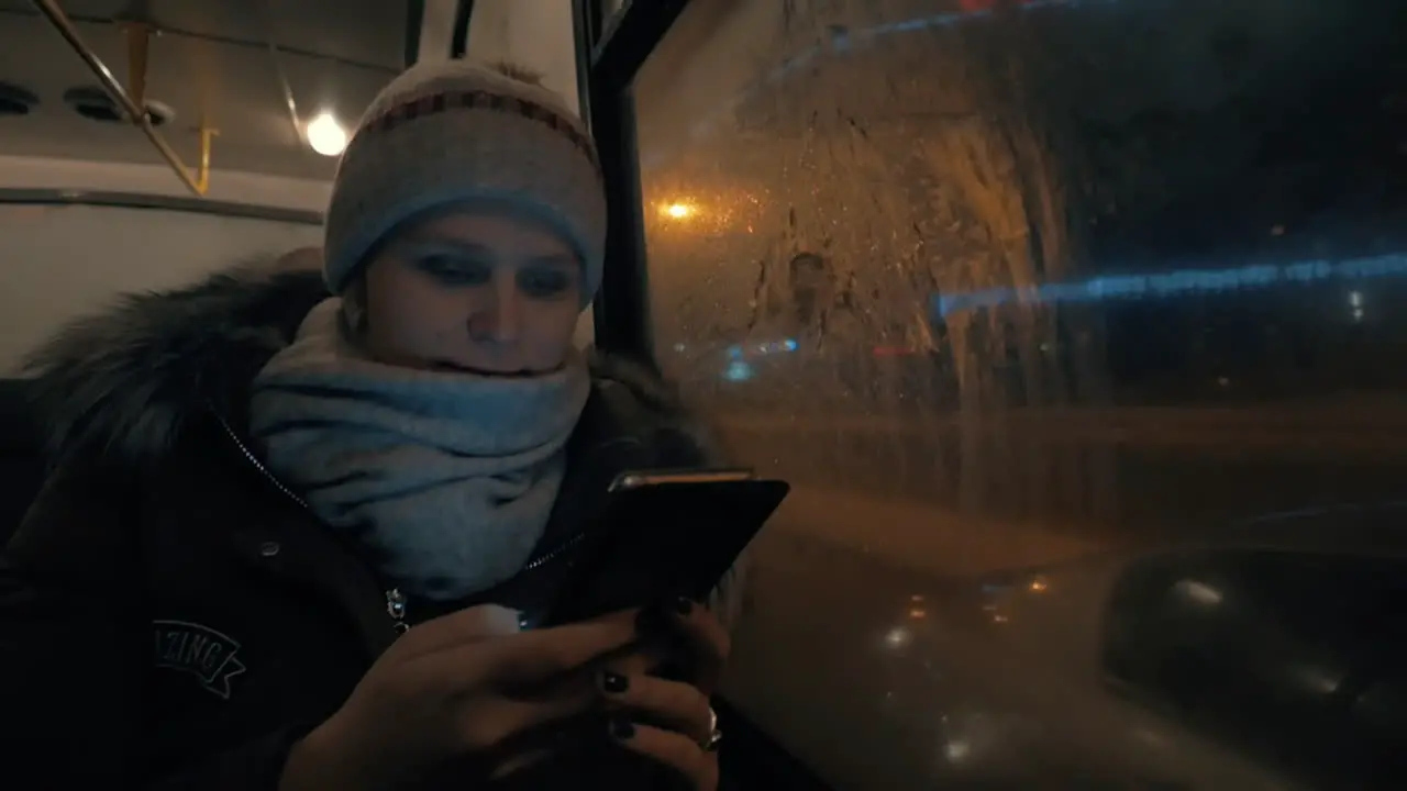 Woman using cell while traveling by bus in night city