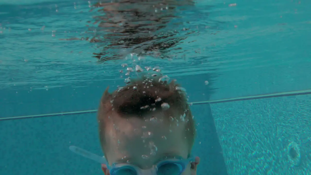 Cheerful boy bathing in swimming pool on summer vacation